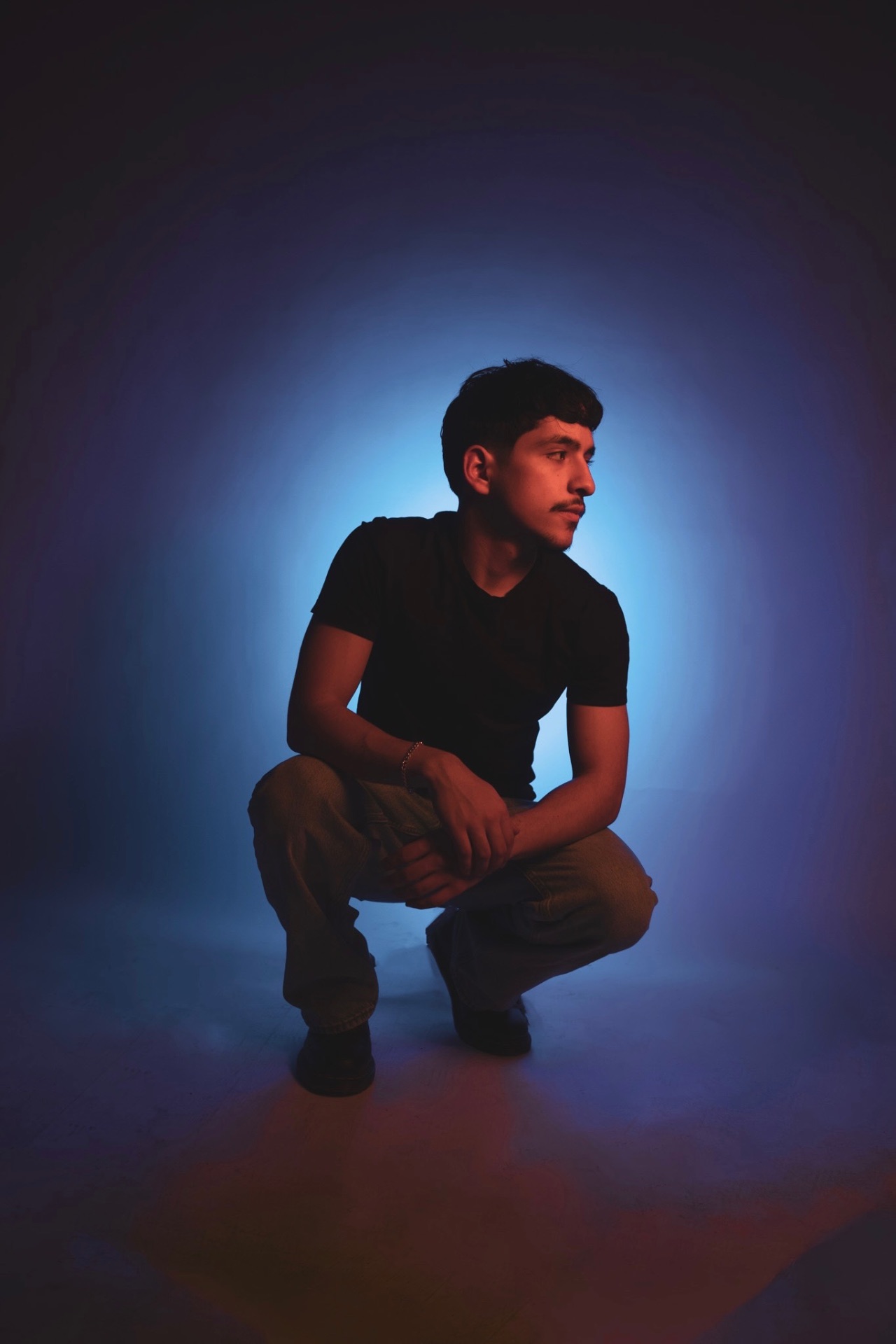 Nestor, founder of Nestorations, crouching in blue studio light